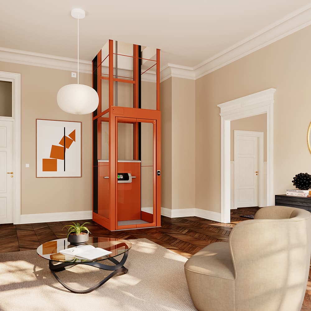 Orange Kalea Luna home lift with glass shaft and glass door, placed in a small corner of a 19th century duplex apartment with beige walls and dark brown, herringbone floors, showing a glass coffee table and a beige armchair in the foreground.